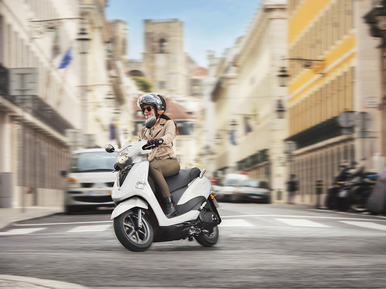 Yamaha D'elight 125 scooter in Milky White riding down city street