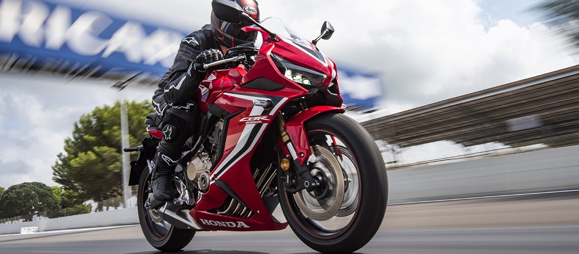 Honda CBR650R in grand prix red colour, being ridden on a race track
