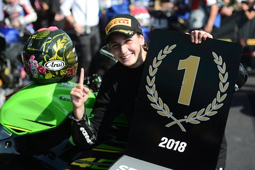 Ana Carrasco Gabarrón holding a number one sign near her green motorcycle