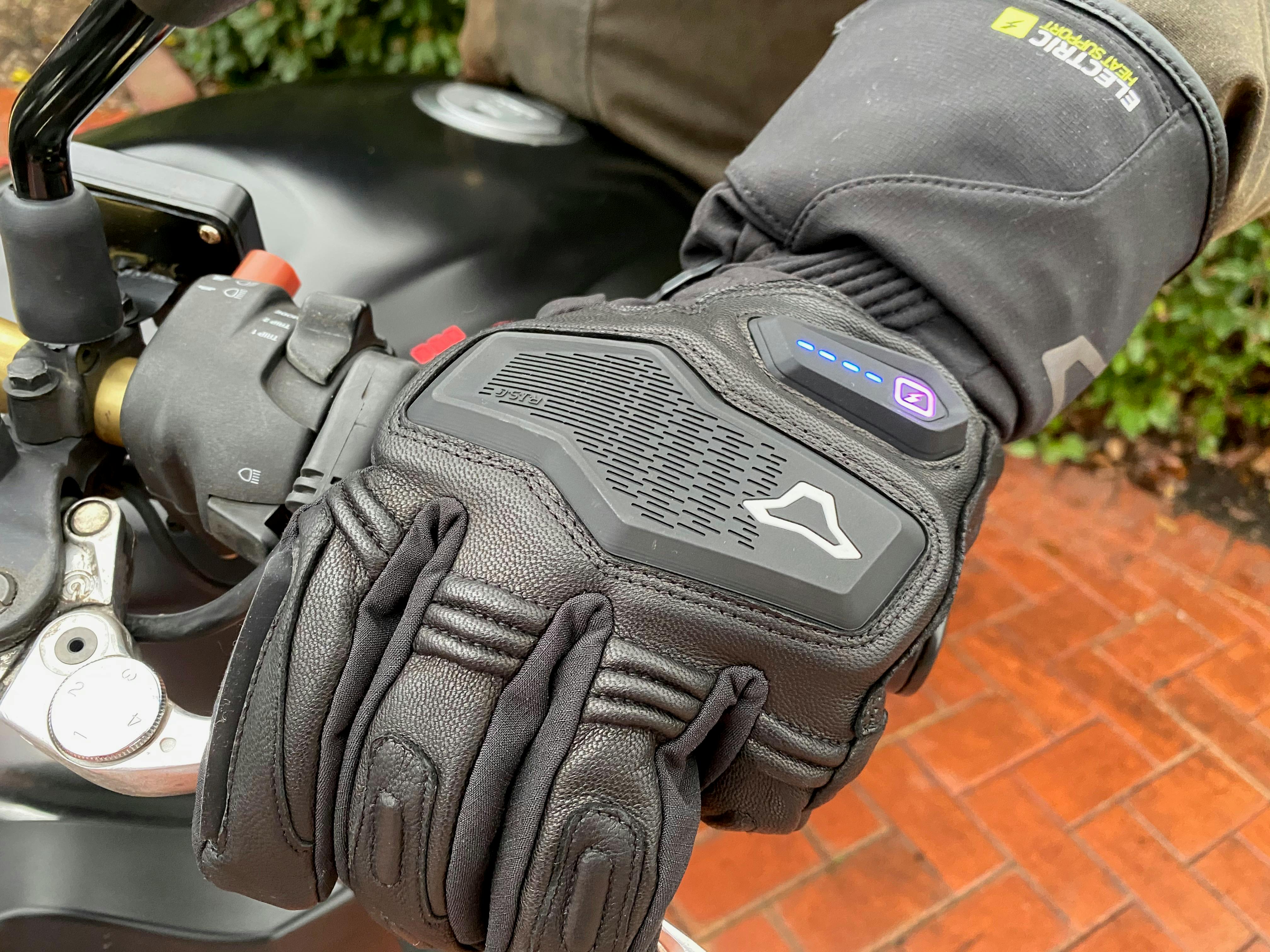 The Macna Ion heated glove on a mans hand on a motorcycle handlebar