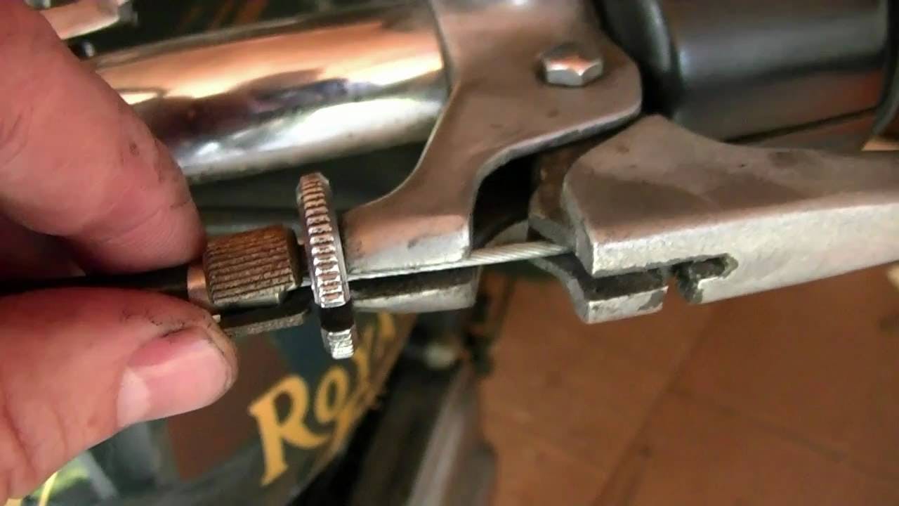 Hand adjusting a cable on a royal enfield motorcycle