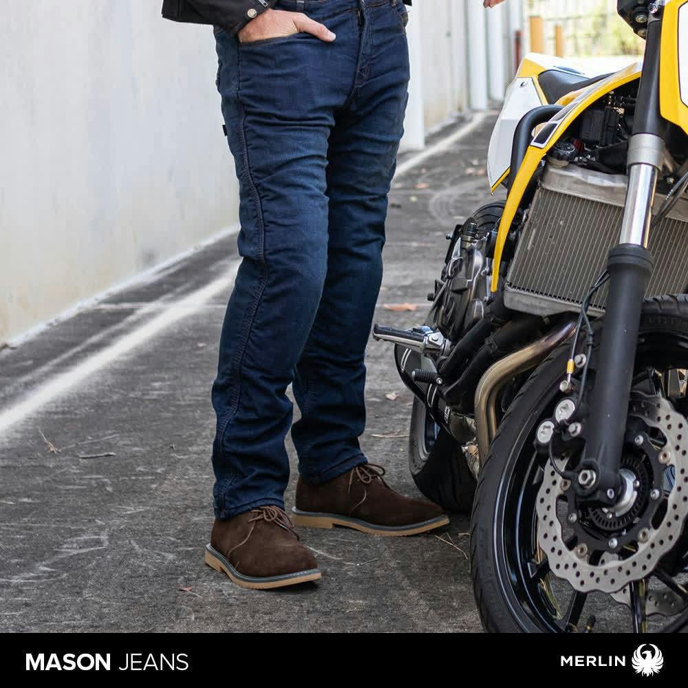 Man wearing the Mason jeans by Merlin next to a yellow motorcycle