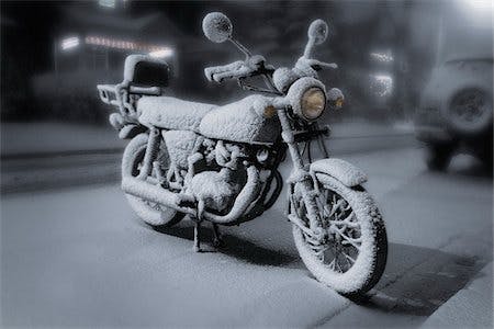 A frozen motorcycle covered in snow on a frozen street