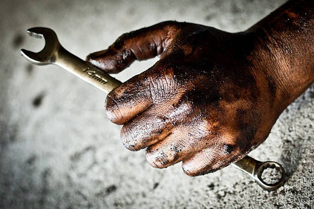 A greasy hand holding a spanner