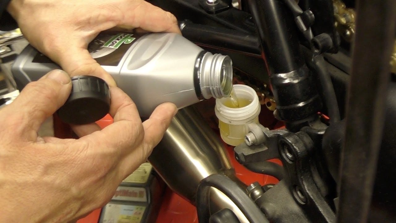 Man pouring brake fluid into a motorcycle