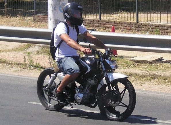 Unsafe motorcycle rider wearing only a helmet and no other safety gear