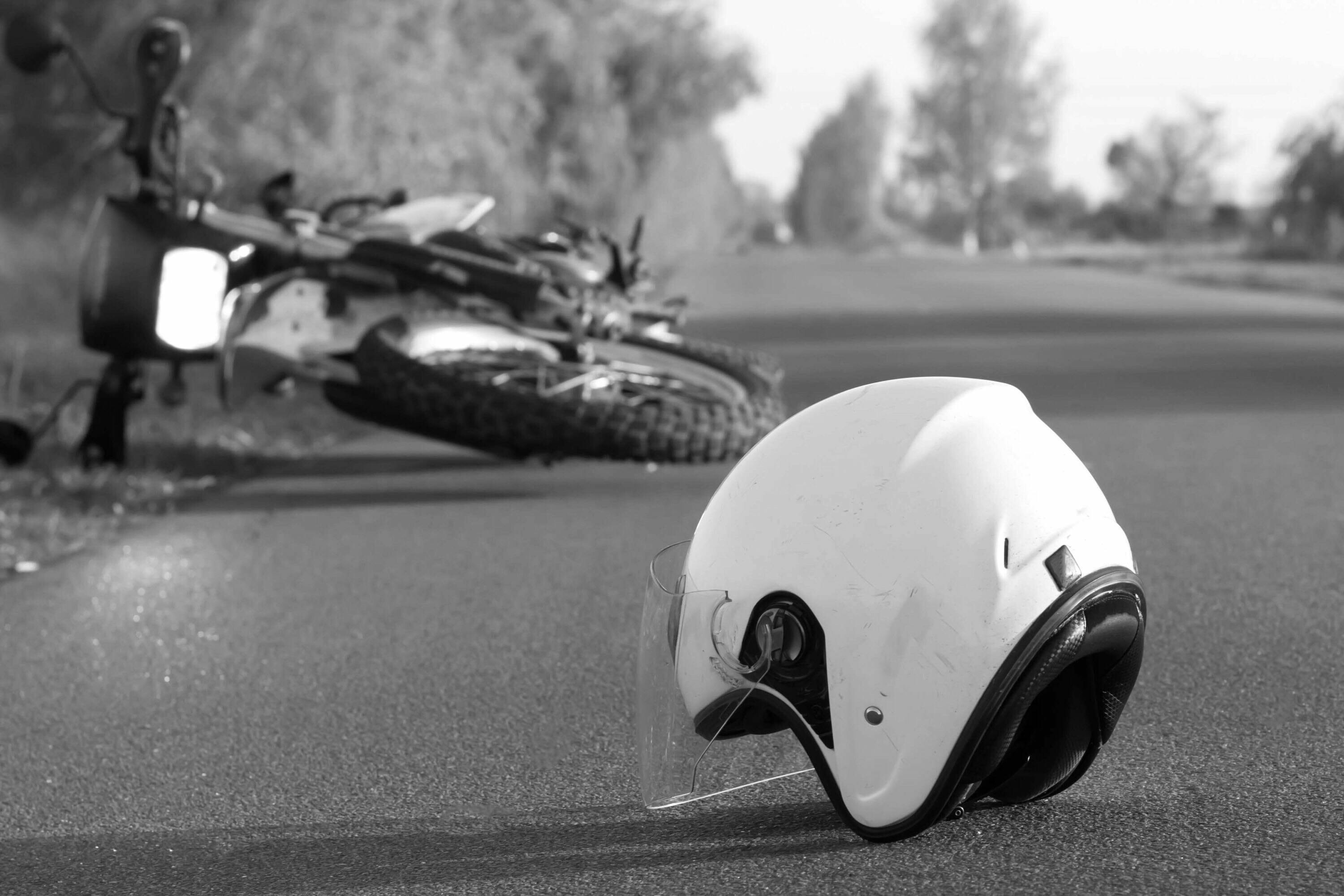 black and white picture of helmet and motorcycle on the side of the road
