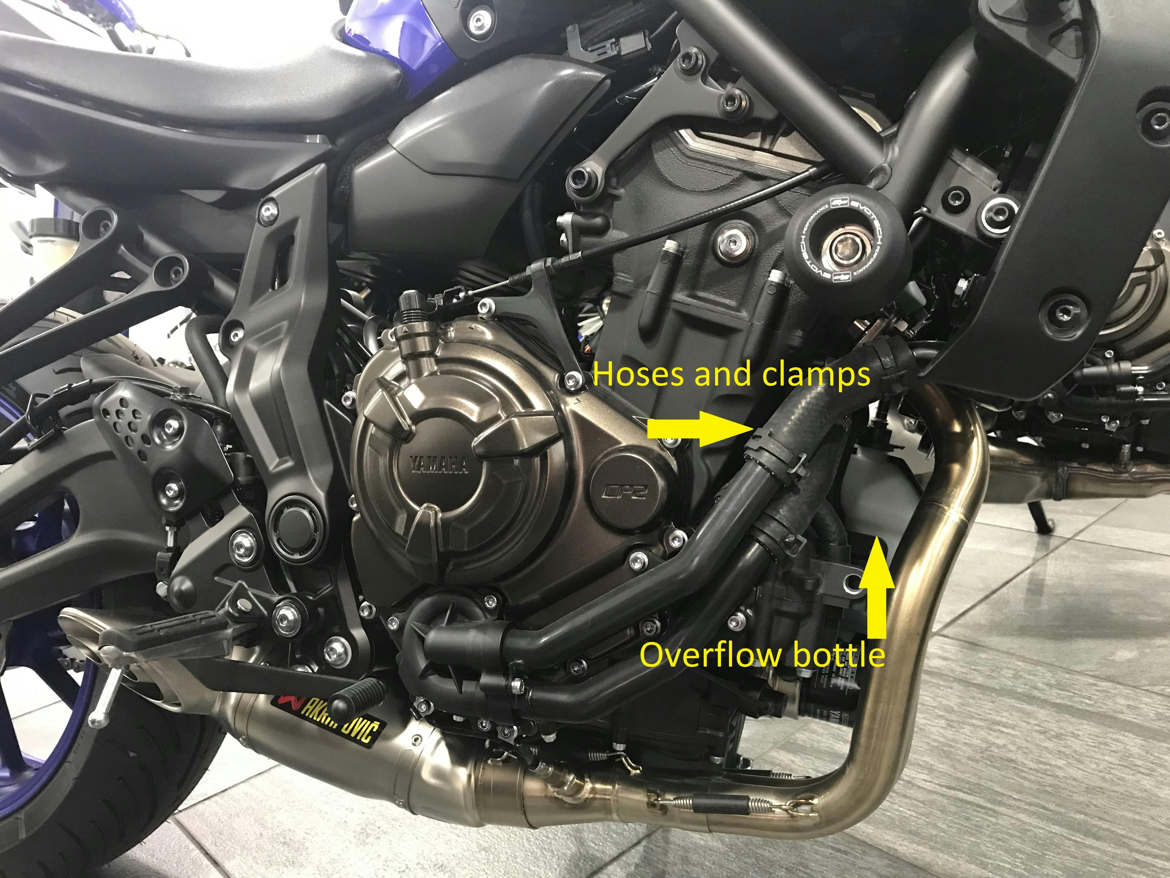 Close up of the side of a motorcycle showing the overflow bottle and radiator hoses