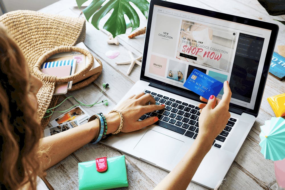 A lady with her credit card online shopping on a macbook pro laptop