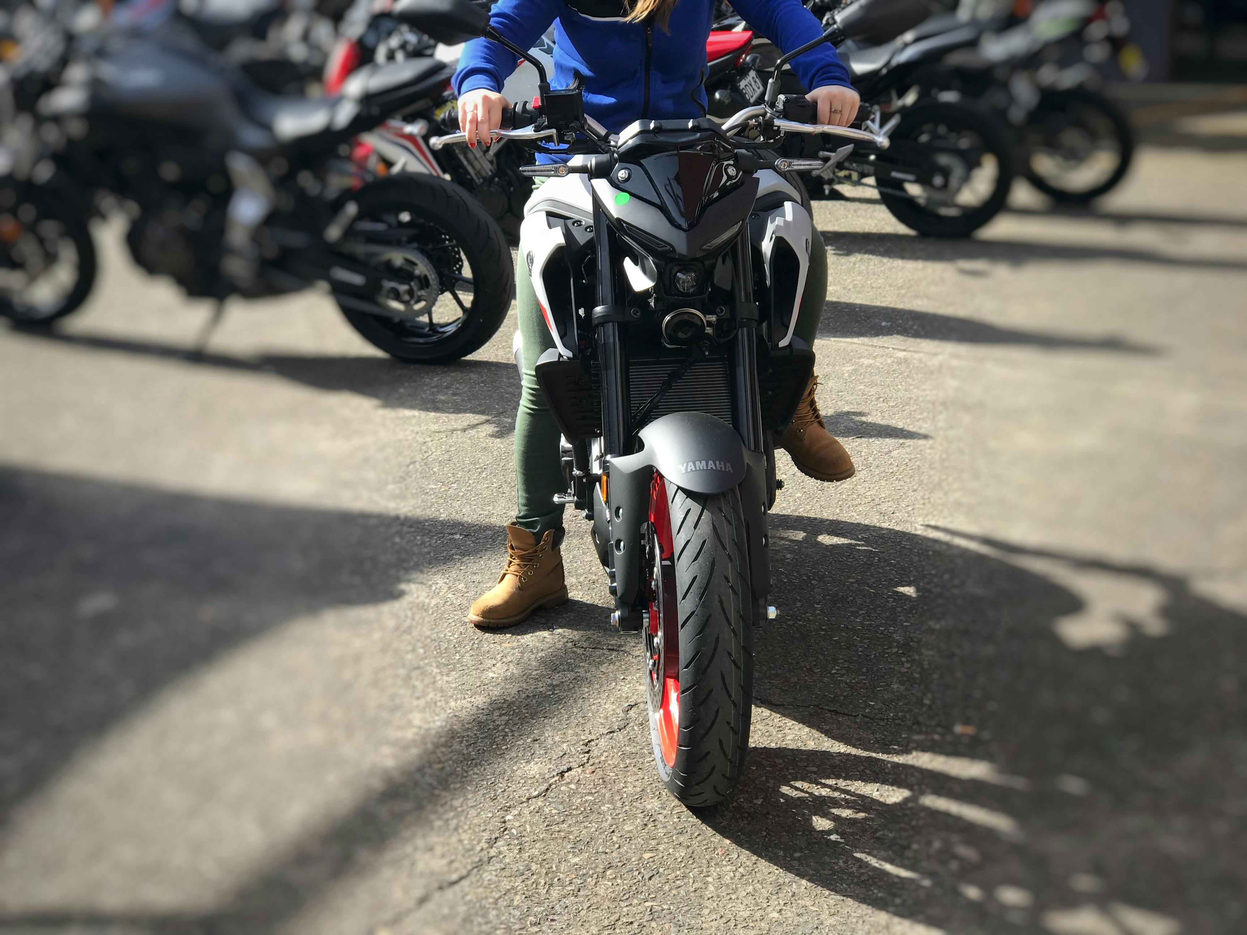 Woman in green pants sitting on a Yamaha MT03 in a car park