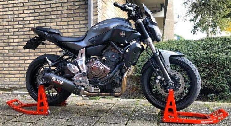 A black Triumph motorcycle on red front and rear stands