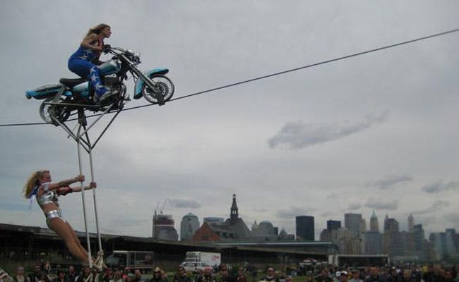 Motorcycle on a high wire with a woman hanging underneath