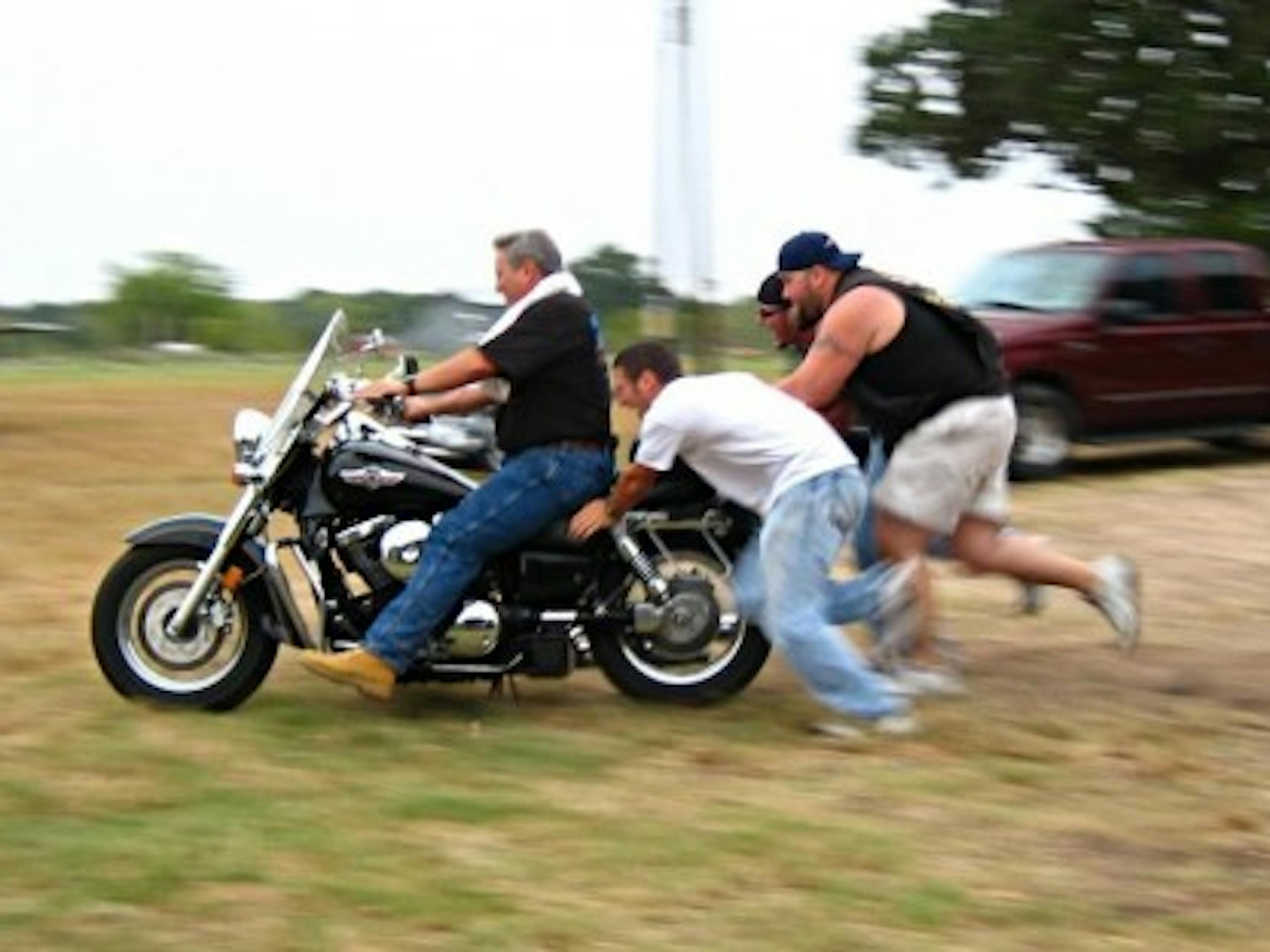 4 men push starting a cruiser motorcycle