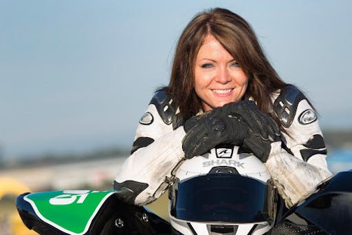 Brunette woman posing with helmet and motorcycle