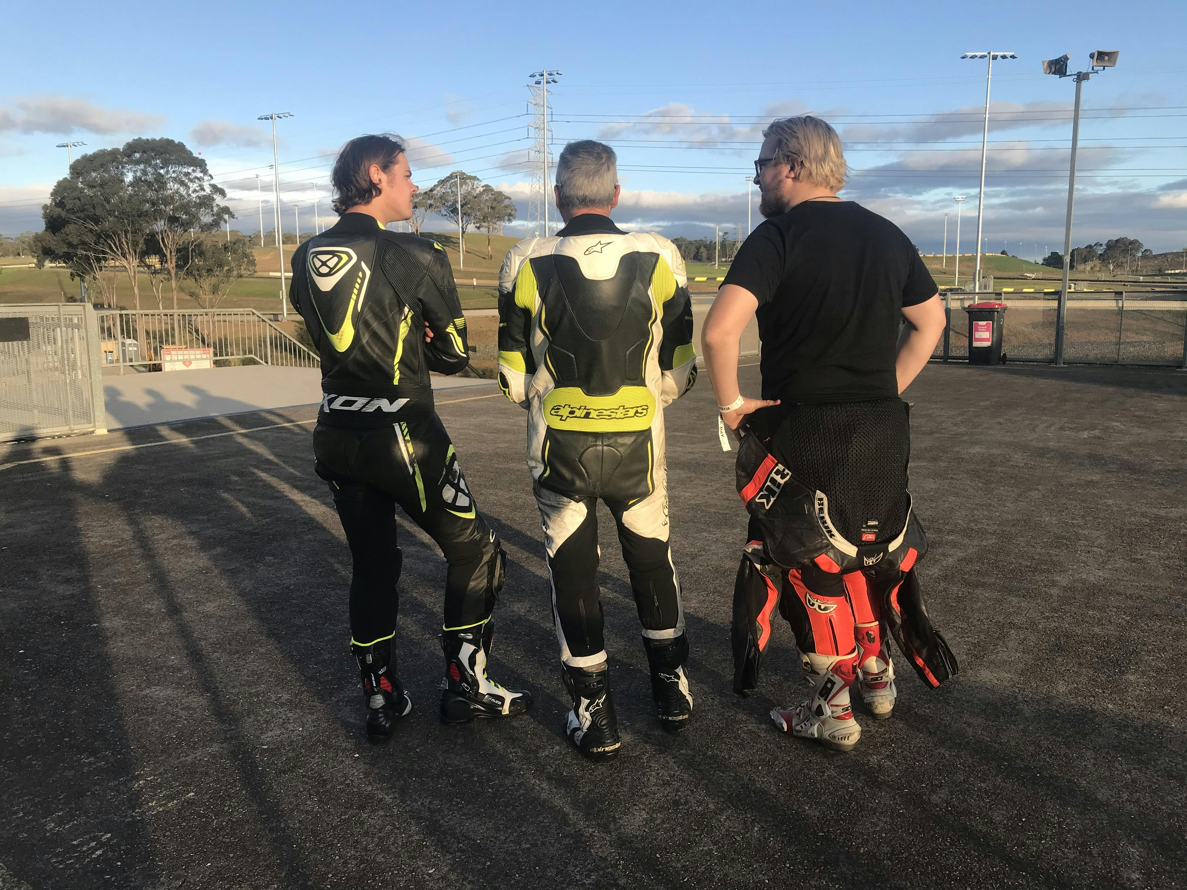 3 guys in leather suits at a race track