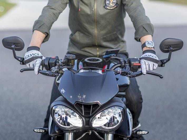 A Quad Lock and phone mount on a black motorcycle with a rider sitting on the bike