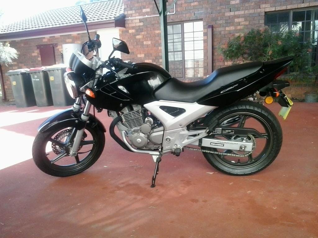 A black and silver Honda CBF250 motorcycle on an orange driveway