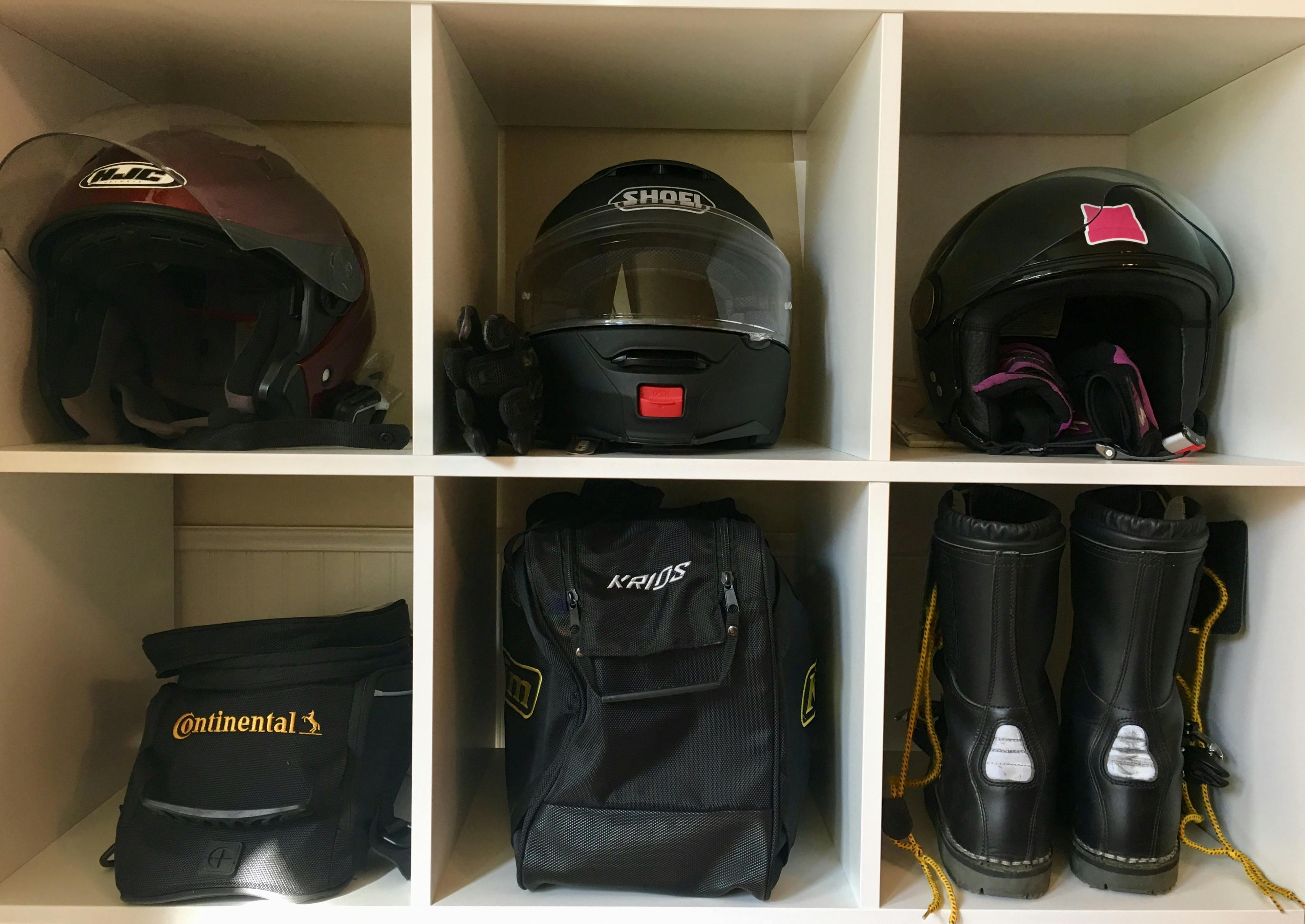 3 helmets, 2 bags and a pair of boots organised and separated