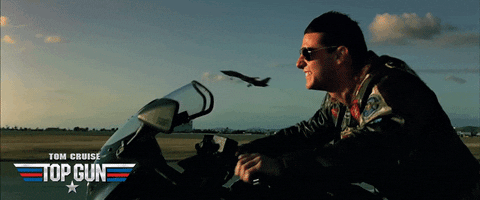 GIF of top gun of Tom Cruise riding a motorcycle while a plane flies in the background
