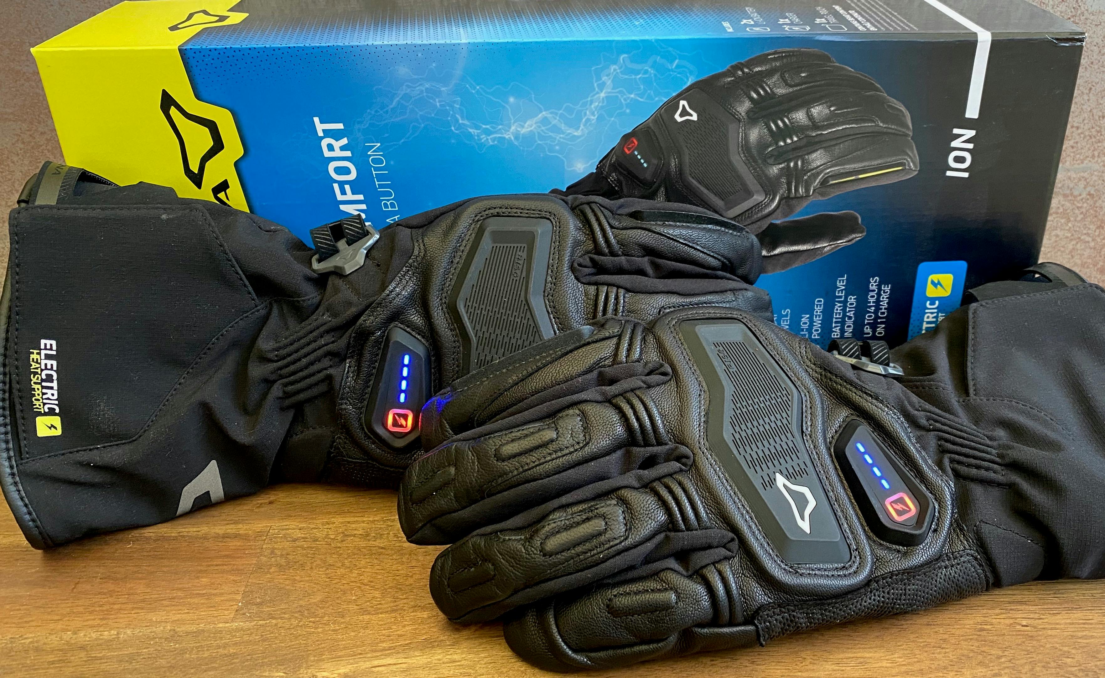A pair of Macna Ion gloves in front of their blue and yellow box