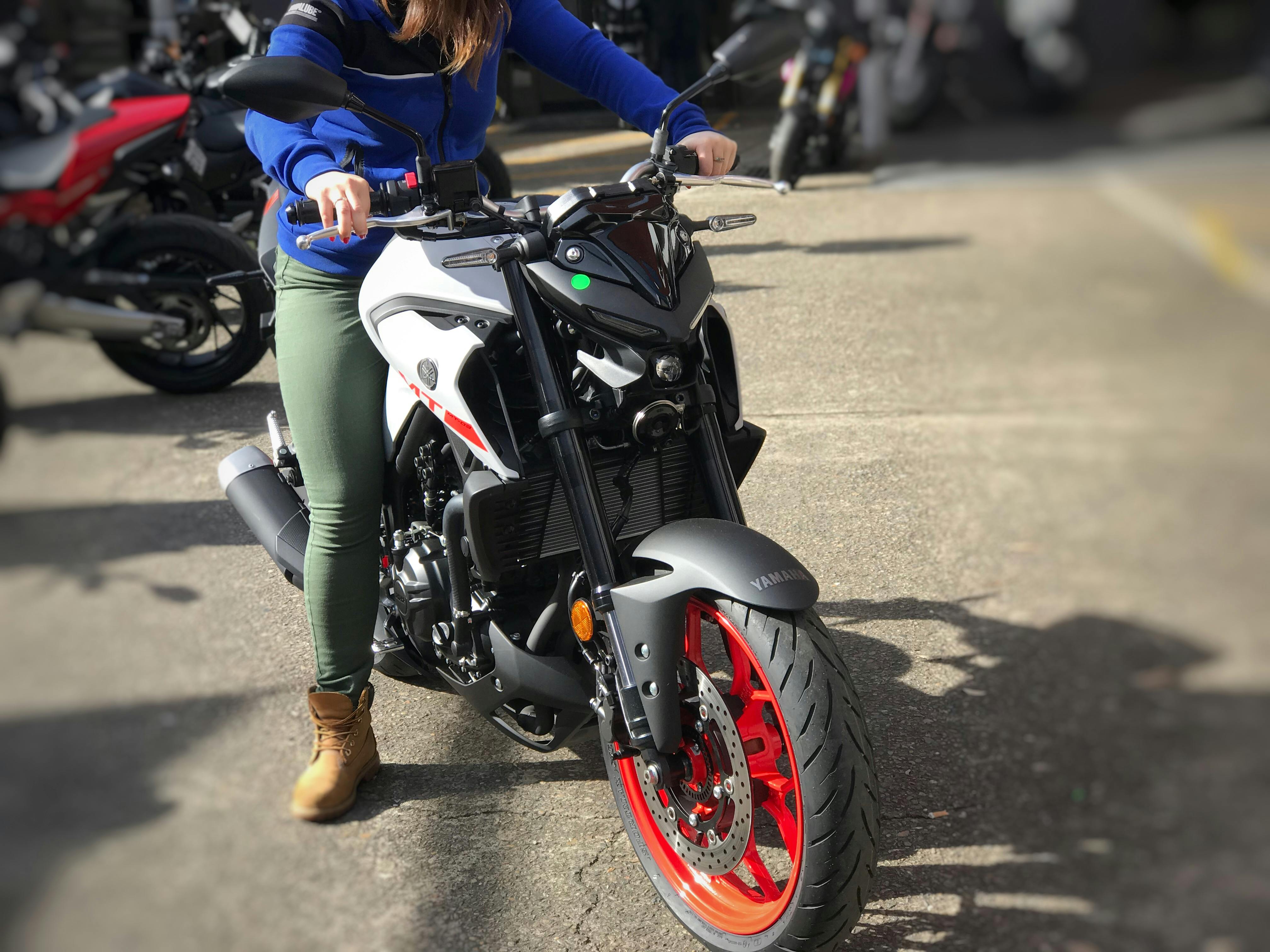 Woman in green pants sitting on a Yamaha MT03 in a car park