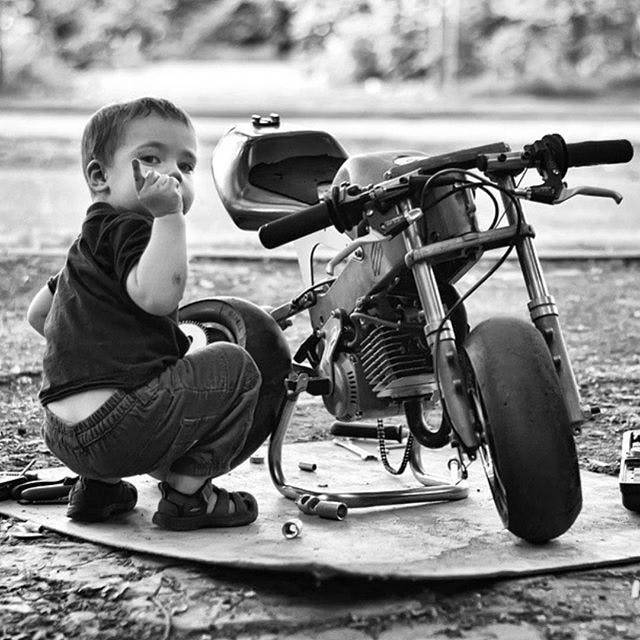 Small child fixing a small motorcycle