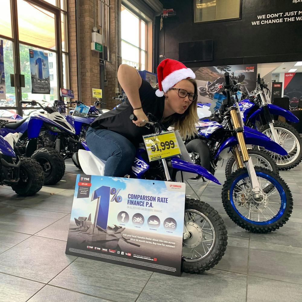 Woman on a PeeWee 50 motorcycle with a Santa hat on