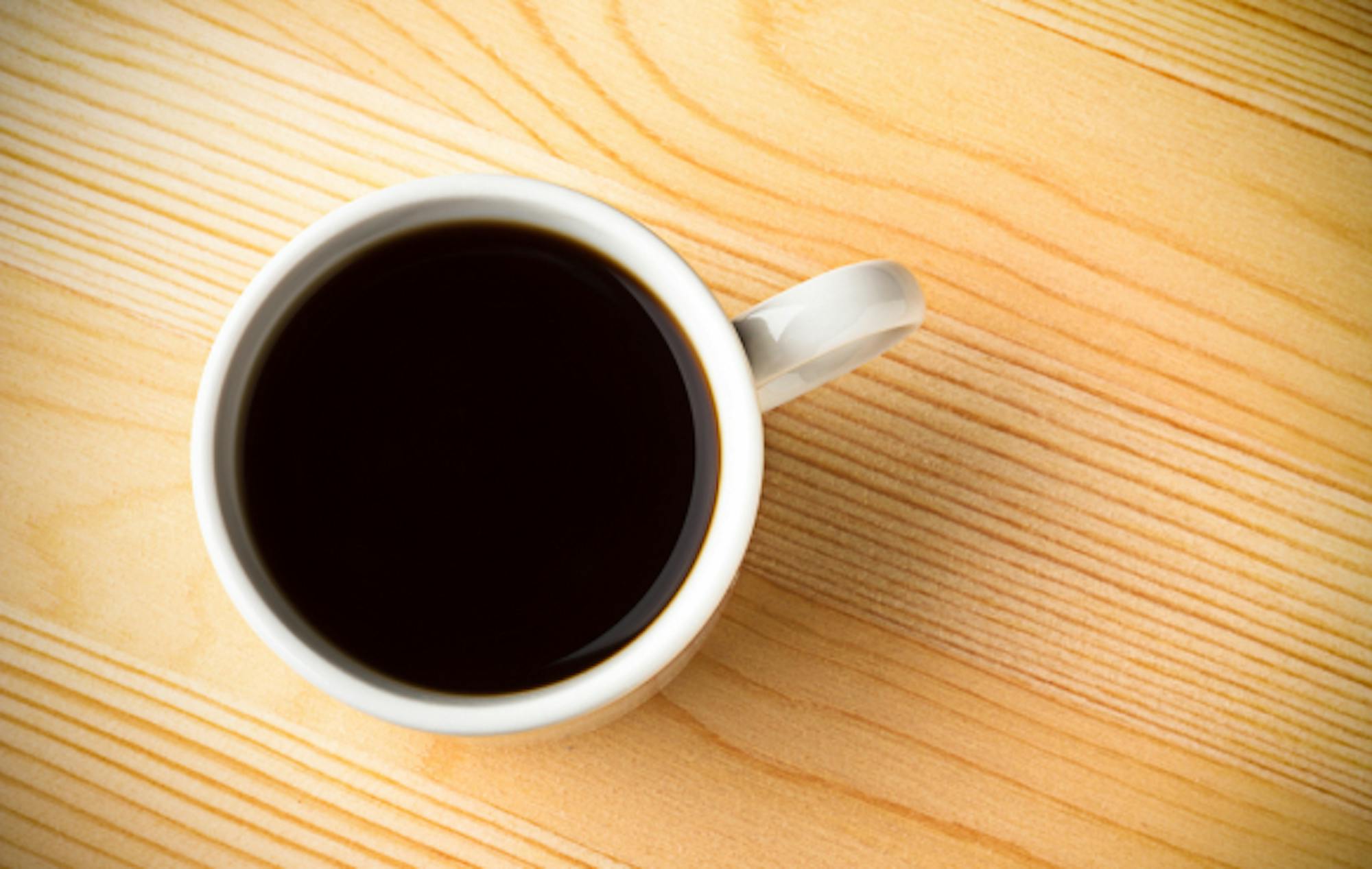 A cup of black coffee on a wooden surface