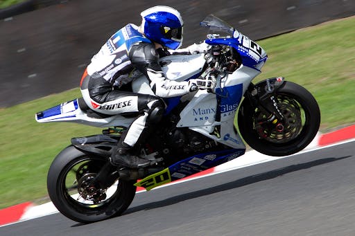Jenny Tinmouth in blue and white leathers racing a blue and white motorcycle