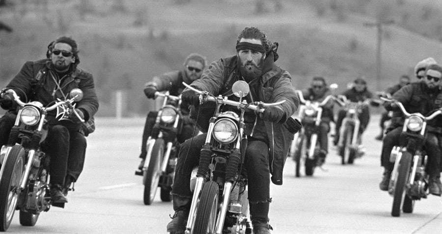A group of motorcyclists with no helmets in black and white
