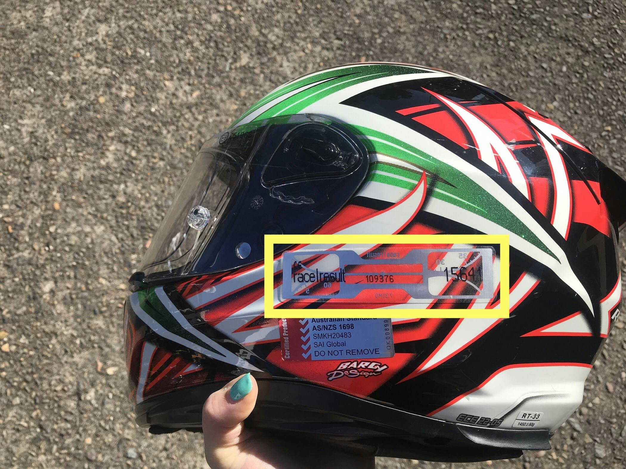 An orange and green Kabuto helmet with a SMSP time tracking sticker highlighted