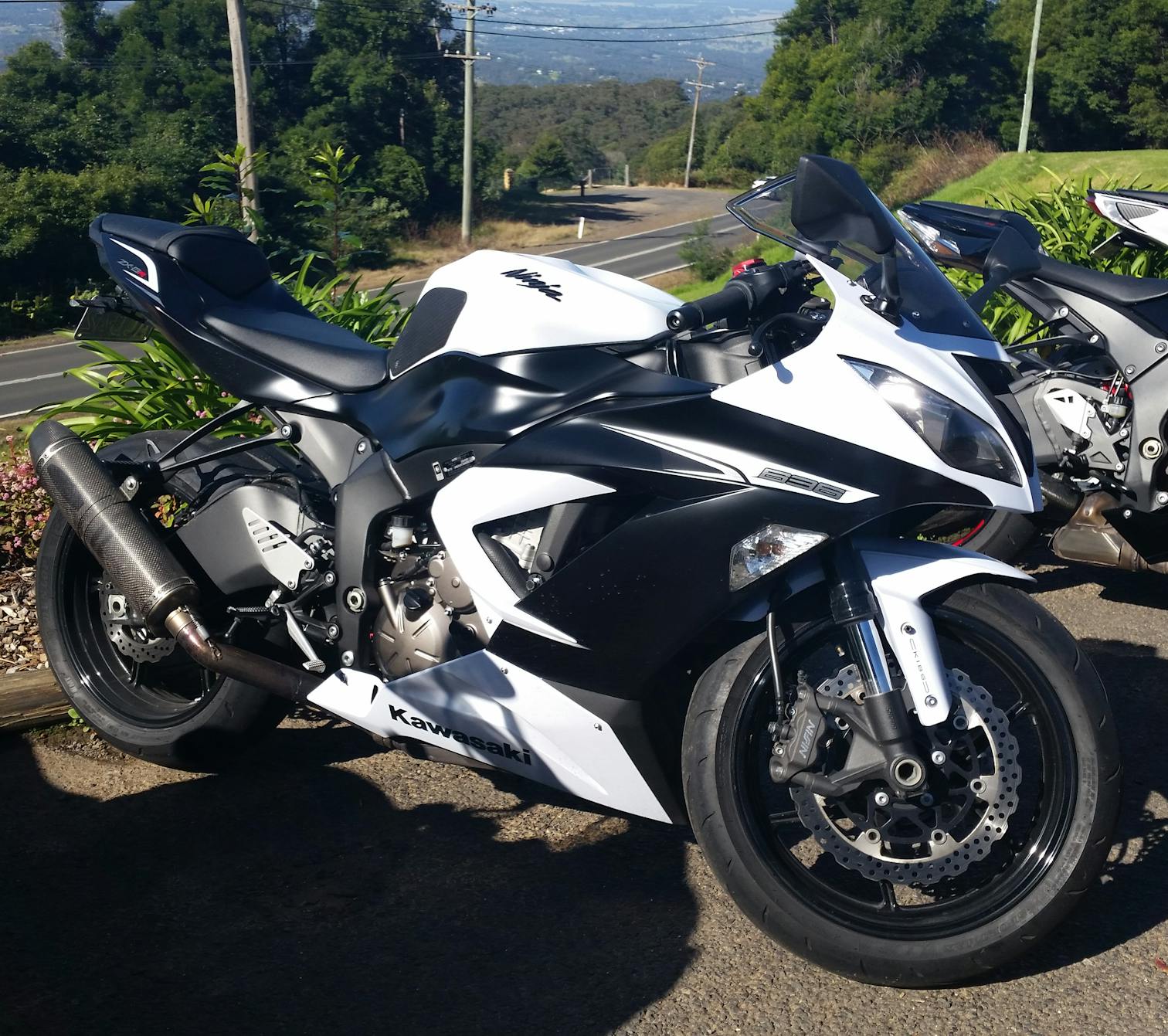 A white Zx636 motorcycle with an Akrapovic slip on exhaust