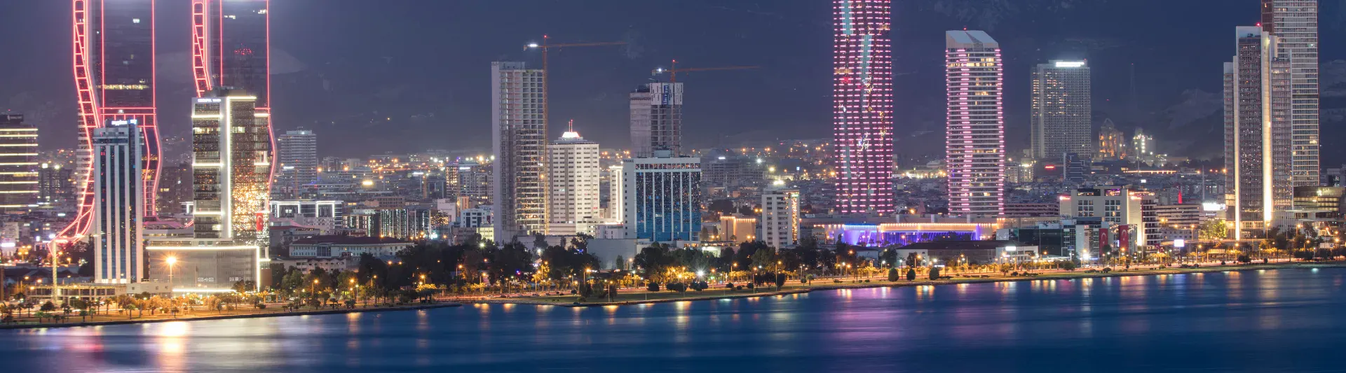 biletiniz.com İzmir uçak bileti arama sayfası kapak görseli; akşam saatlerinde İzmir Körfezi, Bayraklı gökdelenleri ve şehir ışıkları manzarası.
