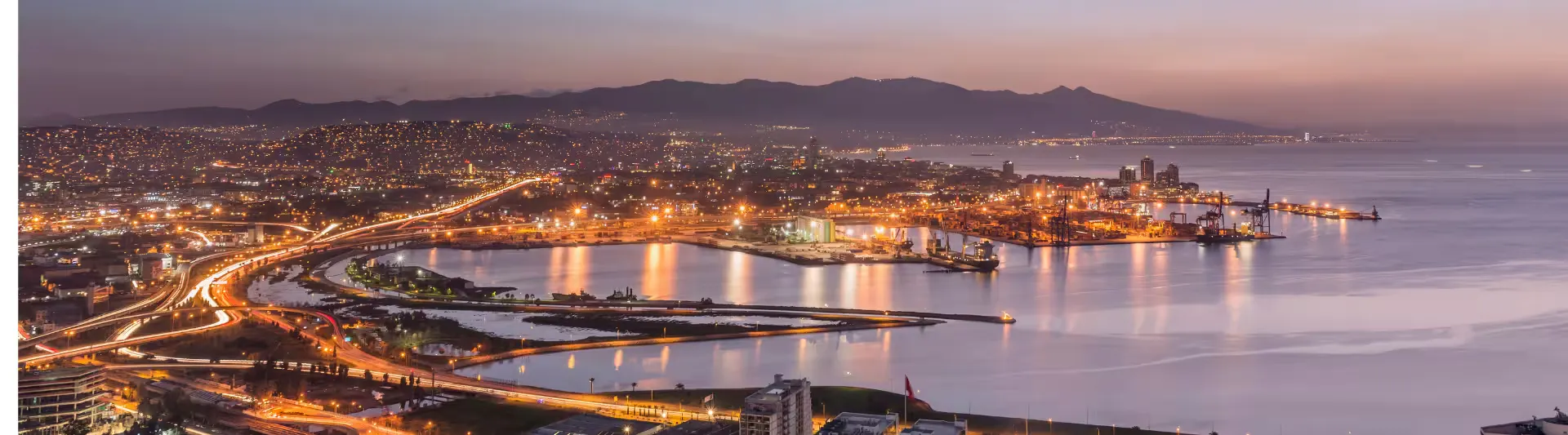 Gece ışıklarıyla parlayan İzmir şehir manzarası ve Körfez görüntüsü eşliğinde en uygun İzmir uçak bileti seyahat rehberi kapak görseli.