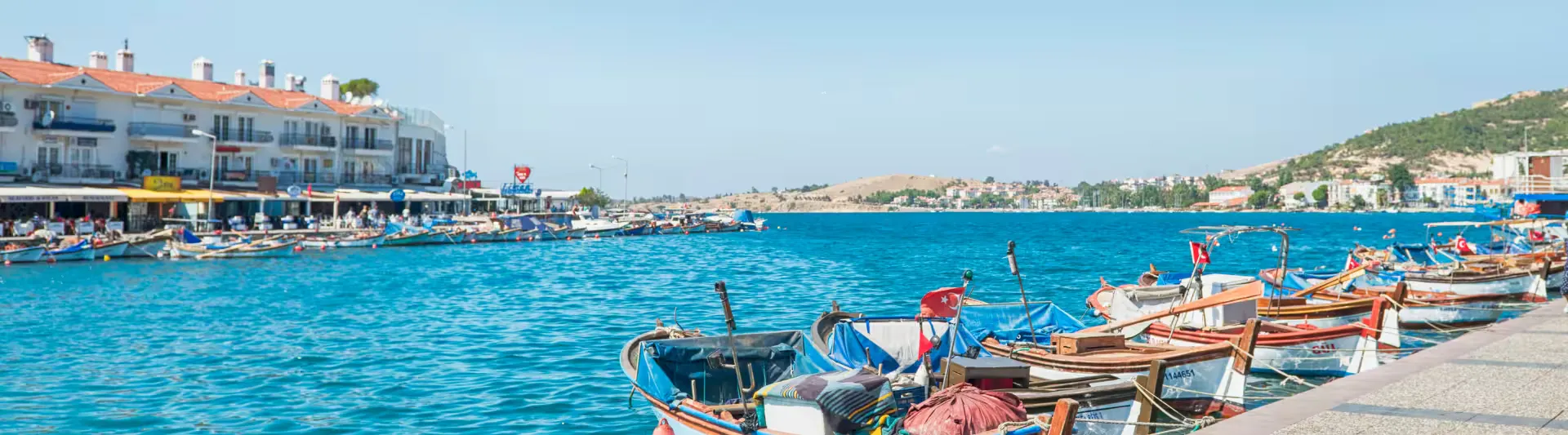 Foça limanında kıyıya çekilmiş ahşap sandallar ve sakin deniz, Bodrum - İzmir otobüs bileti kapak görseli