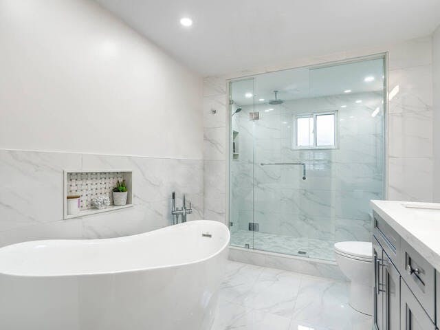 All-white bathroom with marble flooring and a soaking tub