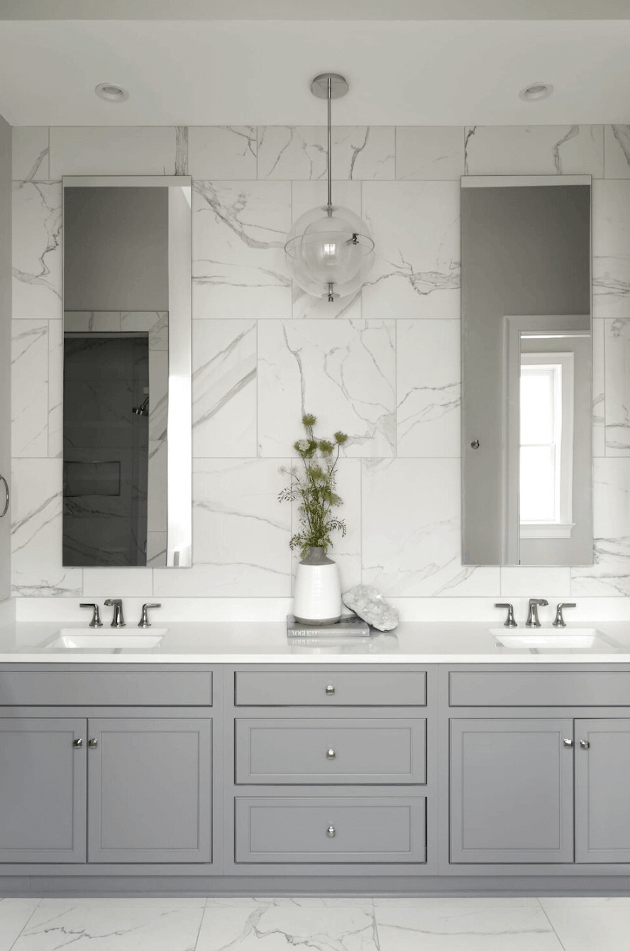 Bathroom with elegant marble tile walls and slim vanity mirrors for a ...