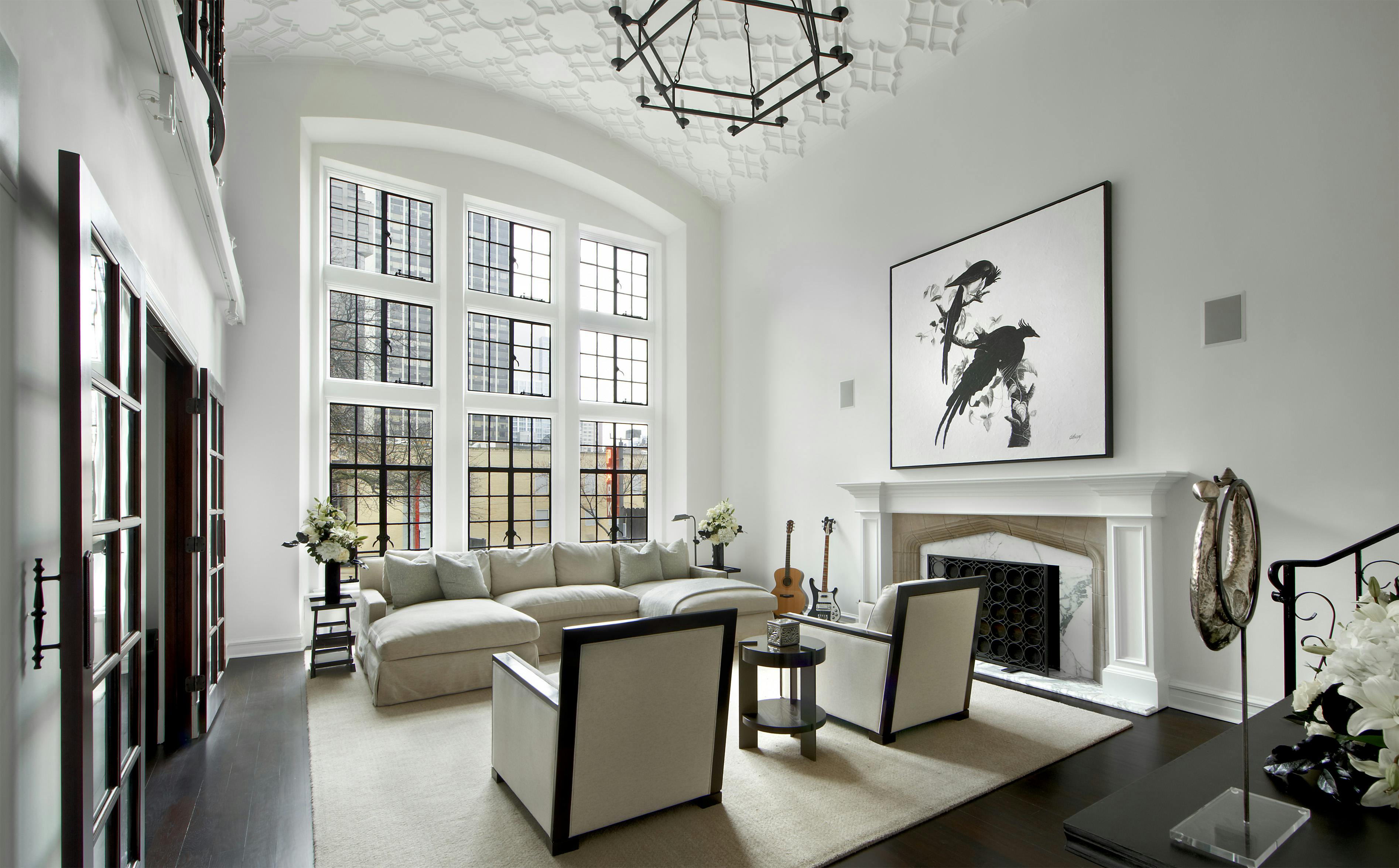 This modern living room features a sleek black and white color scheme, with chic furniture and an elegant ceiling treatment adding to its sophisticated aesthetic. The room's decor is both stylish and functional, making it the perfect place to entertain or relax.
