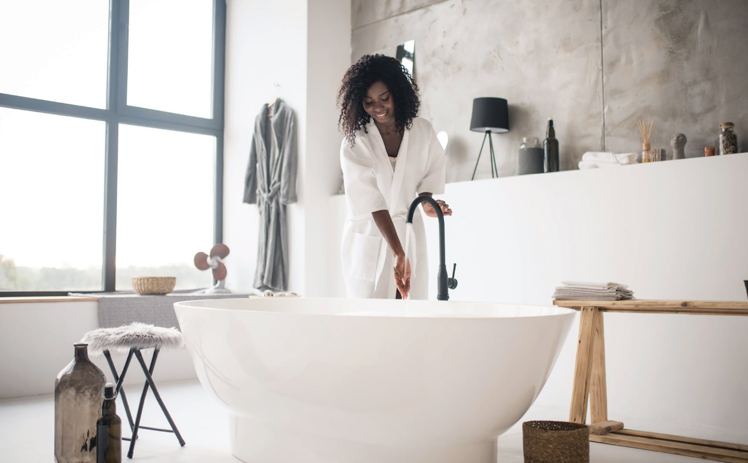 How to give your bathroom the spa treatment in 10 easy steps Woman setting up bath in renovated bathroom