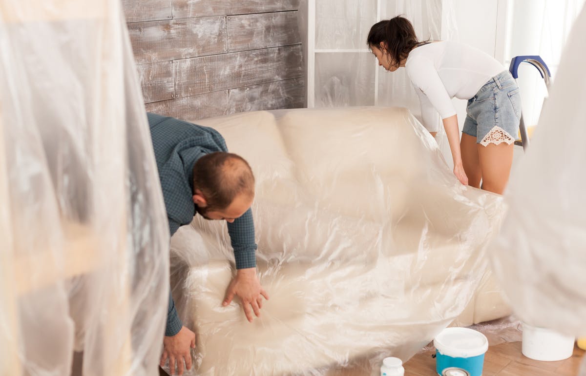 Protect your furniture during renovation Couple covering a couch plastic