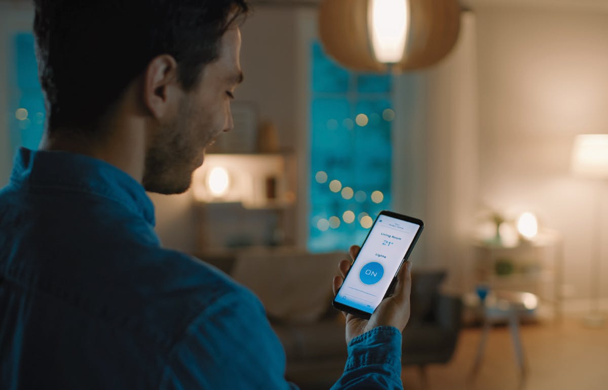Éclairage intelligent de la maison Un homme ajustant son éclairage de maison sur son appareil mobile