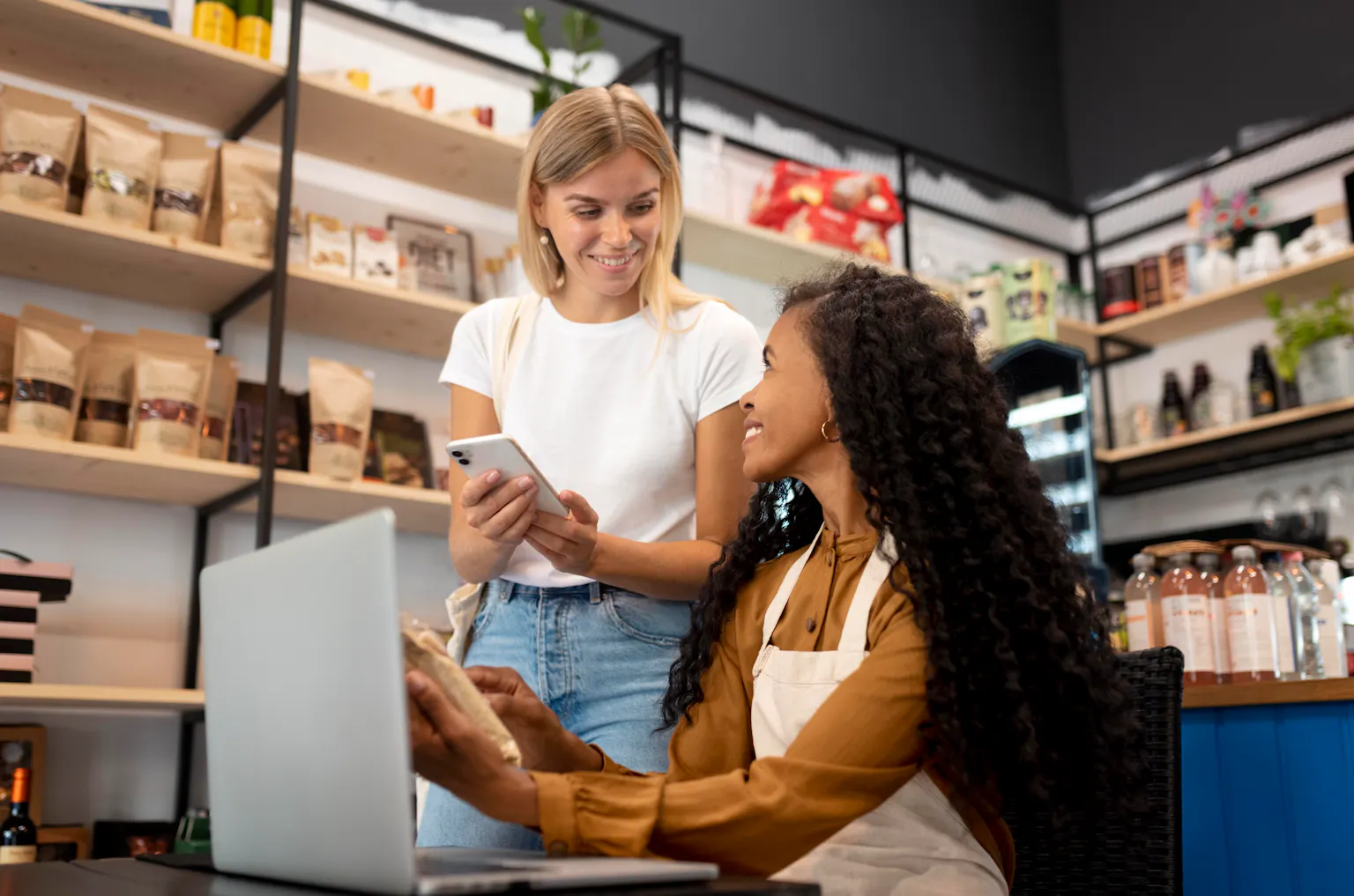 Commerçante et cliente consultant les avis Google sur smartphone et ordinateur