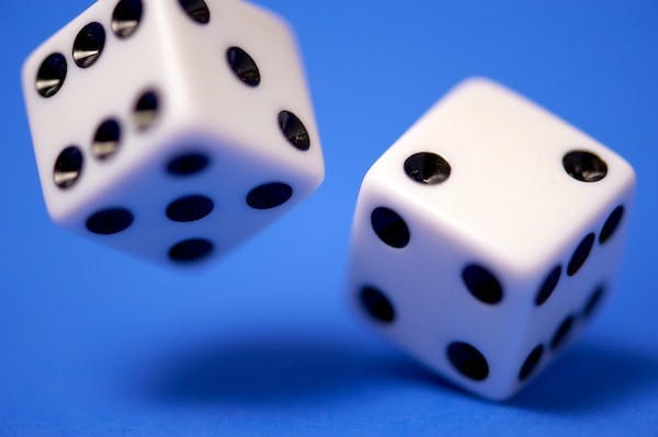 Dice being rolled on a blue background - Photo by Edge2Edge Media on Unsplash