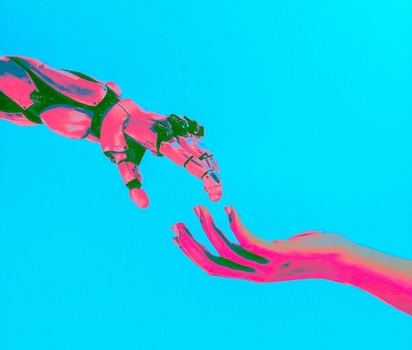 Robot Hand and Human Hand almost touching that are pink and green with a blue background 