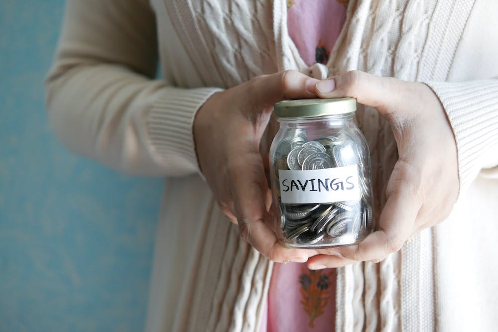 Person holding a jar of coins with label that says savings Photo by Towfiqu barbhuiya on Unsplash