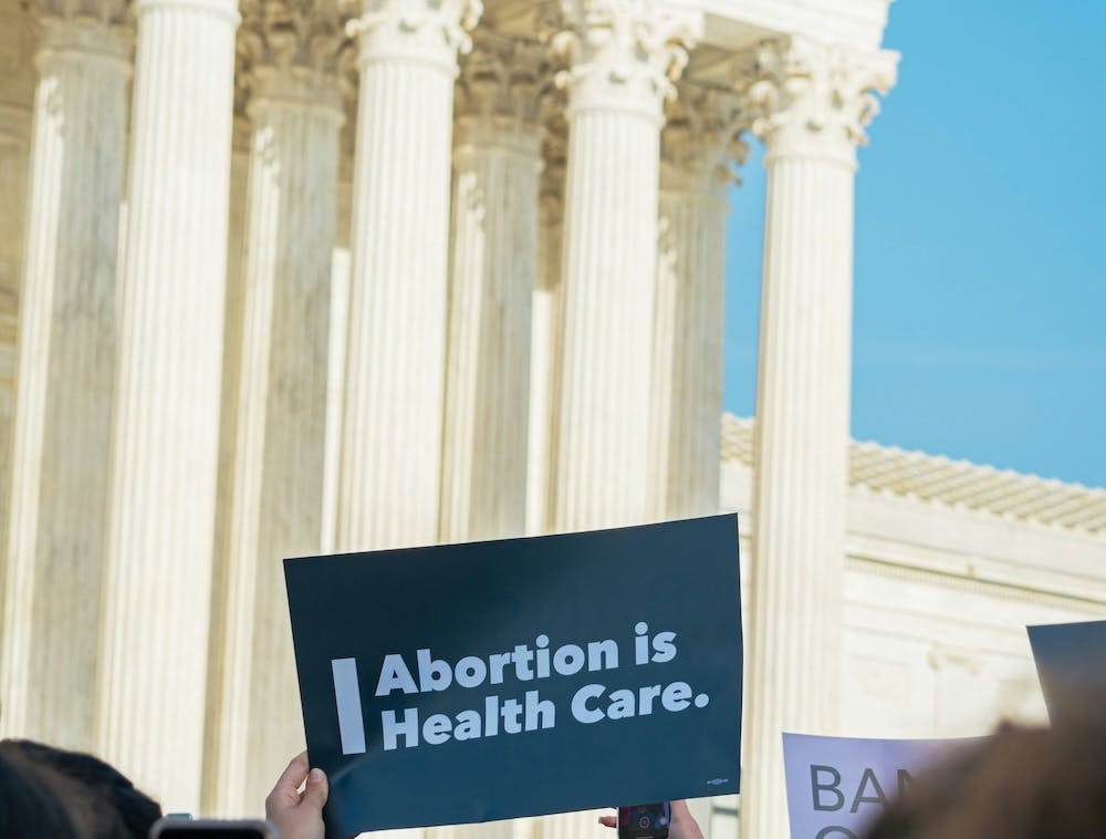 Person holding up sign saying abortion is health care by a federal building in a crowd. 