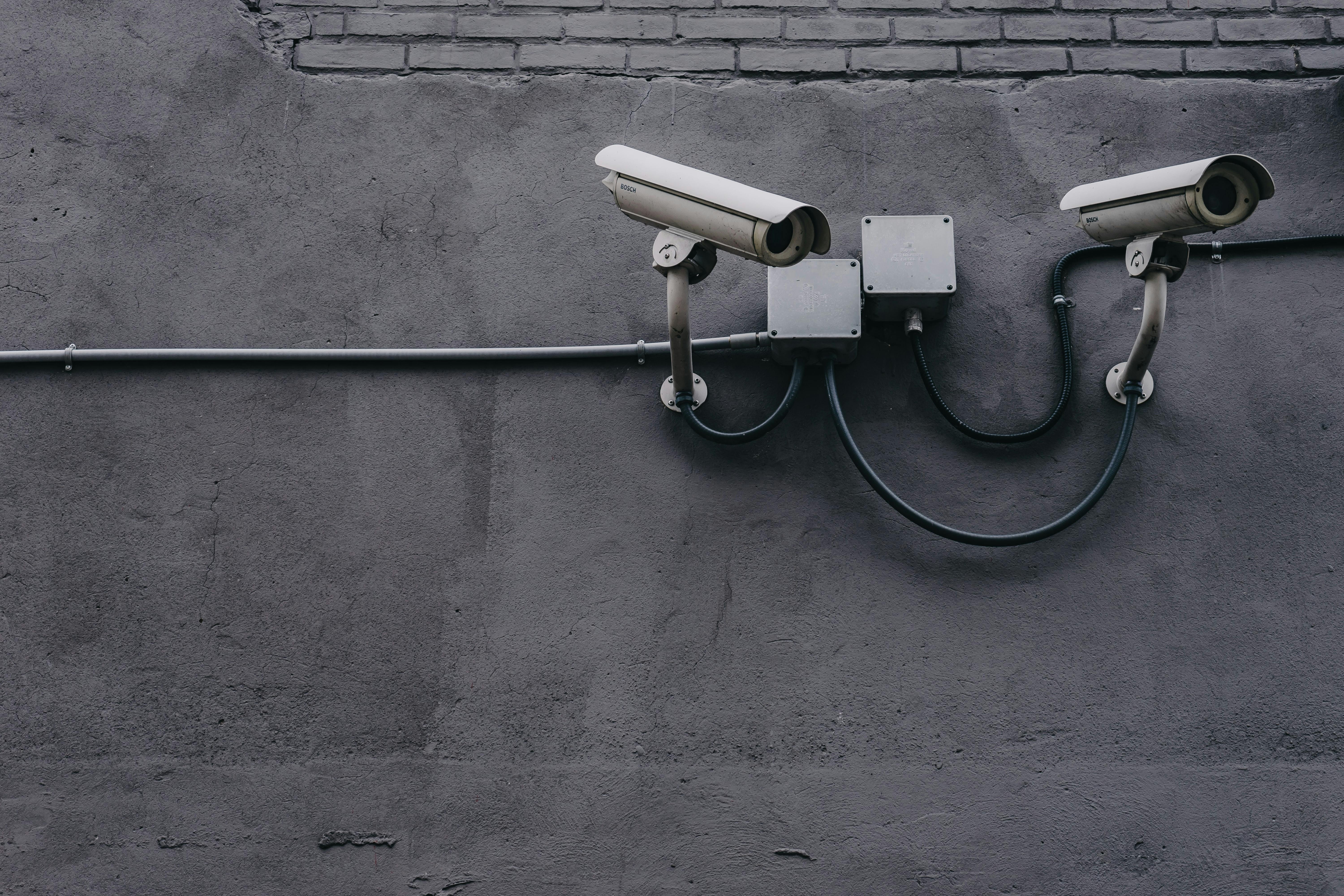 security cameras mounted to a wall - Photo by Scott Webb on Unsplash