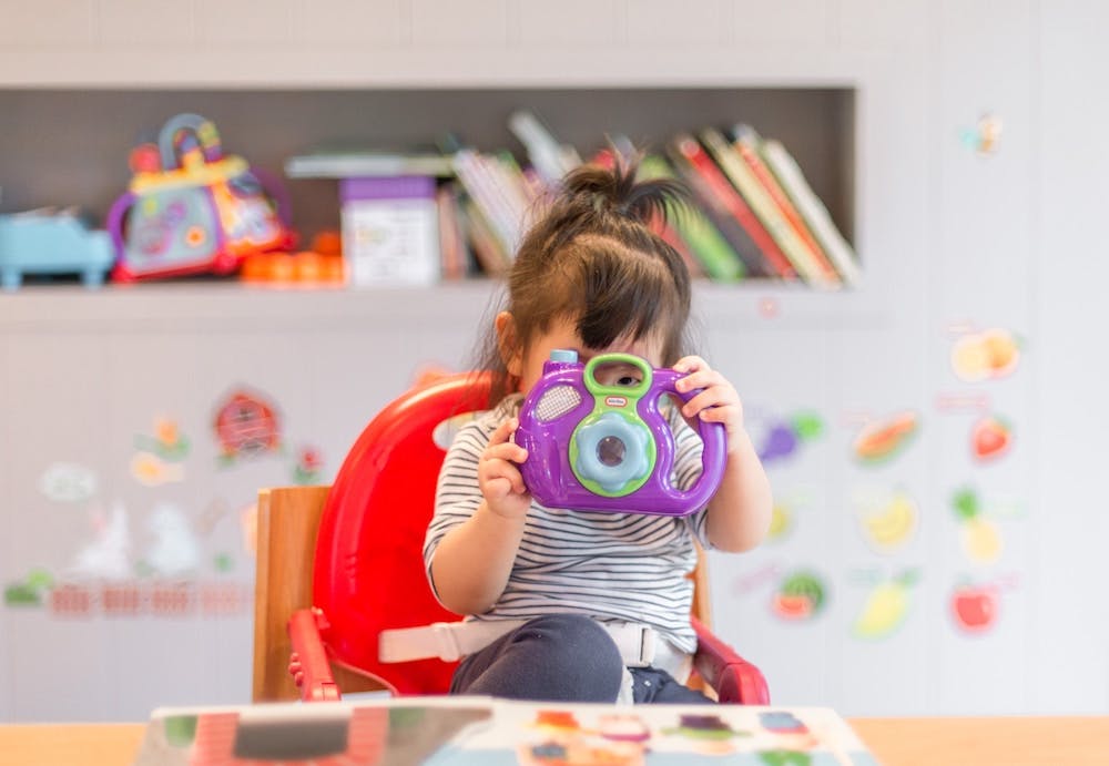 little girl holding a fake camera looking through the viewfinder with her face obscured Photo by Tanaphong Toochinda on Unsplash 