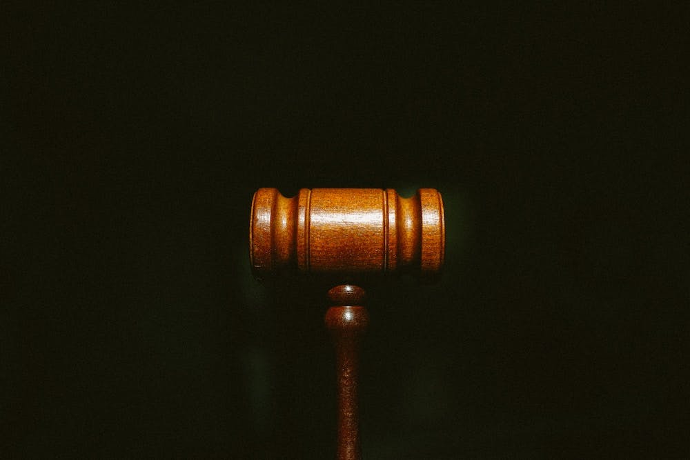 Brown wood gavel on pitch black background. Photo by Tingey Injury Law Firm on Unsplash

