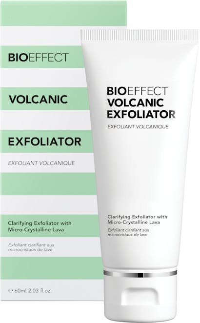 A bottle of BIOEFFECT Volcanic Exfoliator sitting upright, in front of its green and white striped packaging.